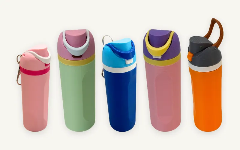 Five 3D-printed mini water bottle keychains in a row: pink, sage green with a pink lid, blue, pink with a purple lid, and orange with a grey lid